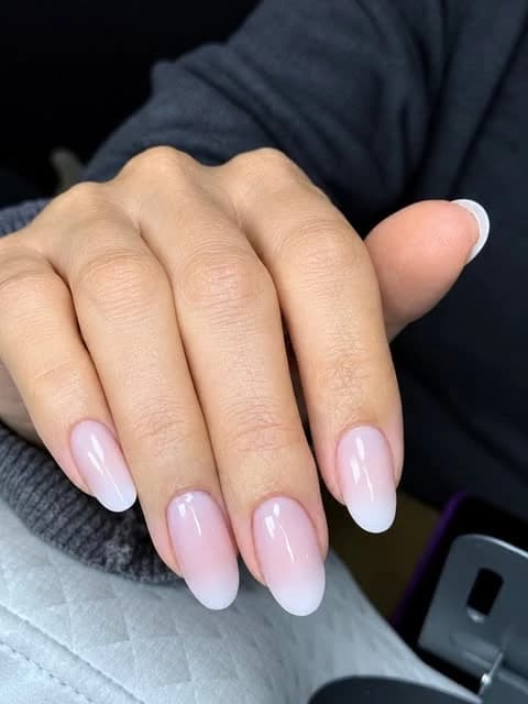 Unhas com degradê suave entre rosa e branco, em formato amendoado