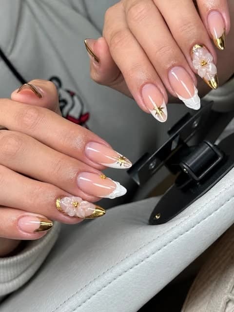 Unhas com francesinha branca e dourada, flores em relevo e detalhes de estrelas